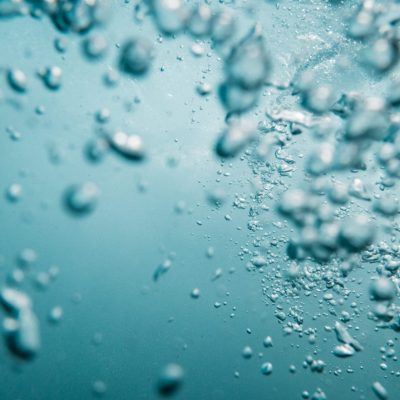Underwater View of Bubbles In Deep Blue Ocean. Close Up Water. Background
